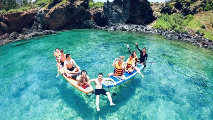Du khách đang trải nghiệm hoạt động chèo SUP trên làn nước biển trong xanh tại Phú Quý, một hoạt động hấp dẫn trong combo của Nụ Cười Mê Kông