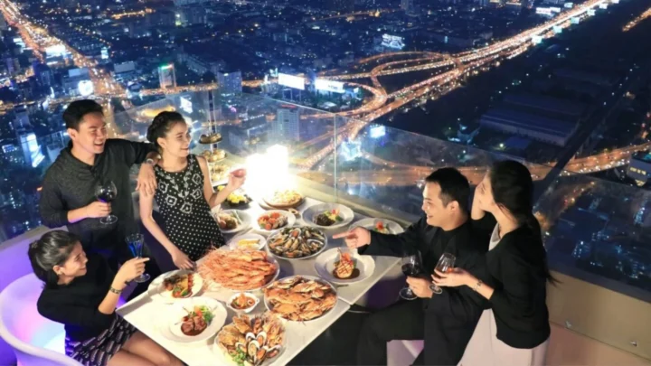 Du khách dùng buffet bên cửa kính với khung cảnh Bangkok trải rộng phía sau