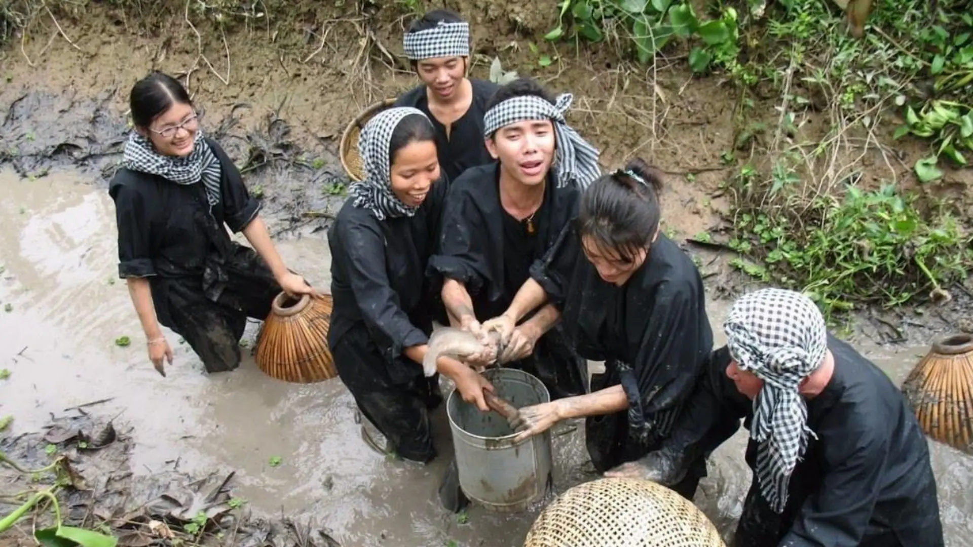 Nhóm du khách mặc đồ bà ba tát mương bắt cá tại khu du lịch sinh thái