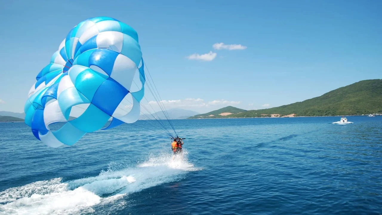 Toàn cảnh Coral Island với cano cao tốc và du khách tham gia dù lượn.