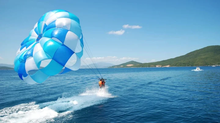 Toàn cảnh Coral Island với cano cao tốc và du khách tham gia dù lượn.